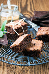 Traditional backed American brownies served as close-up on a rustic cake plate on a wooden board