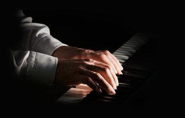 Musician plays on piano with two hands. Isolated focus and light. Male bright hands © irekpod
