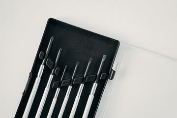 Close-up of container with small screwdrivers for watches on white background