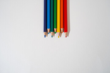 Colored rainbow pencils lie on a white background