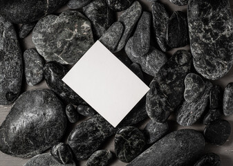 white blank  business card on black stones or galet ,concept of zen spa or sauna branding .