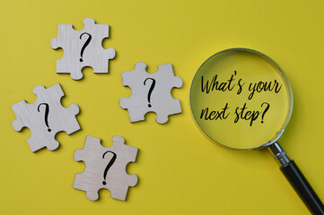 Question mark drawn on wooden jigsaw puzzle with text WHAT'S YOUR NEXT STEP?