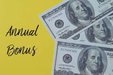 Money banknotes on a yellow background with text ANNUAL BONUS