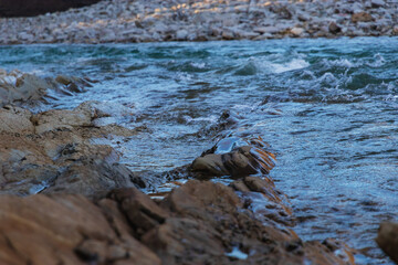 The seething water of a mountain river with a rocky shore on an autumn day. Nature of the foothills of the Caucasus.