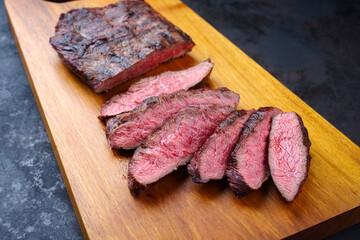 Traditional barbecue wagyu gourmet bavette steak served as close-up on a modern design wooden board