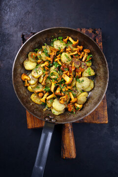 Traditional fresh chanterelles with fried potatoes and parsley served as close-up in a classic skillet