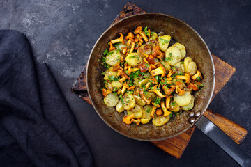 Traditionelle frische Pfifferlinge mit Bratkartoffeln und Petersilie serviert als Draufsicht in einer klassischen Bratpfanne
