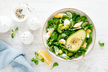Easter fresh vegetable salad with boiled egg, broccoli, corn salad, green peas and avocado, top view