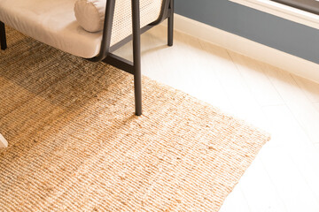 Stylish wicker rug on floor in living room.