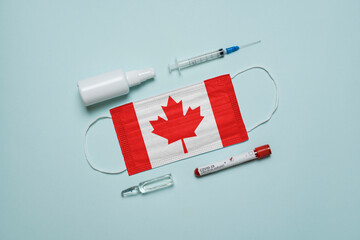 Blood tube for test detection of virus Covid-19 Omicron Variant with positive result, medicine mask with Canada flag superimposed and vaccine.  New Variant of the Covid-19 Omicron - 475728203