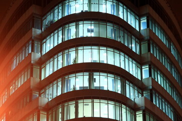 The facade of a round glass building with large panoramic windows and balconies at night, the...