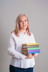 A woman 40-44 years old with a stack of books in her hands. Vertical photo