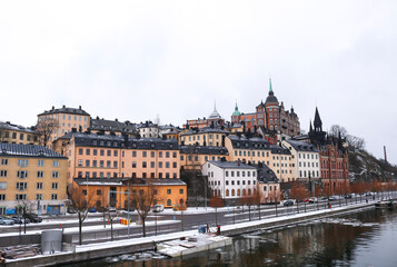 Fototapeta na wymiar Snow Södermalm buildings atop the icy riverside, Stockholm, Sweden.