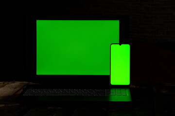 a phone with a green screen lies on a black laptop on a table, a phone template with a screen