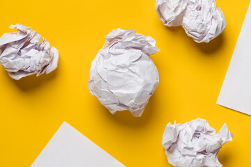 Balls of crumpled paper and white sheets of paper in the form of triangles, with space for text. Yellow background. Copy space. 