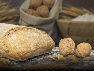 Bodegón de pan de nueces. pan de nuez con nueces en un saco, trigo seco, harina en un cuenco de madera y espolvoreado