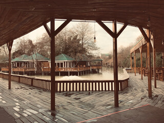 Street cafe with simple wooden interior on the shore of a picturesque lake. Authentic cafe with wooden tables and chairs near the Achigvar lake. Part of the terrace of the summer restaurant behind a w