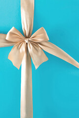 Christmas gift with shiny ribbon and bow on turquoise blue background. Minimal holiday composition.