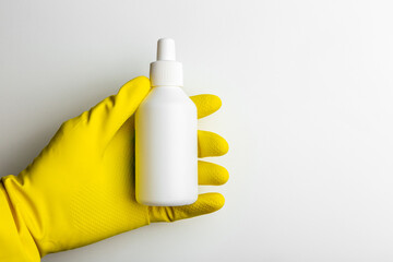a hand in a rubber glove holds an blank white container