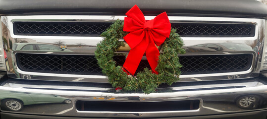 Holiday wreath with red bow mounted on truck grille.