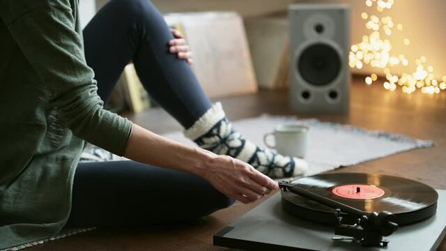 Young woman listening to music at home, Turntable playing vinyl LP record. Girl wearing warm winter clothes relaxing and having fun. Leisure, music, hobby, enjoying life, lockdown, lifestyle concept