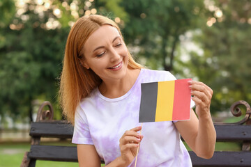 Fototapeta premium Mature woman with flag of Belgium sitting on bench in park