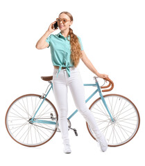 Fototapeta na wymiar Pretty teenage girl with bicycle talking by mobile phone on white background