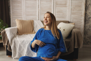 A modern pregnant girl in a bright blue suit at the 30th week of pregnancy enjoys pregnancy. The...
