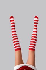 Legs of sexy young woman in Christmas stockings on light background