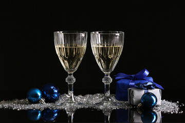 Glasses of champagne, Christmas decorations and gift boxes on dark background