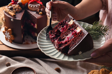 Woman eating piece of tasty Christmas chocolate cake, closeup