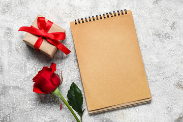 Empty notebook with gift and rose flower on grunge background
