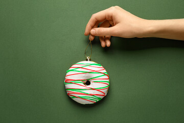 Female hand with tasty Christmas donut on green background