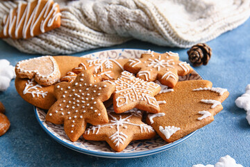 Plate with tasty gingerbread cookies on blue background, closeup