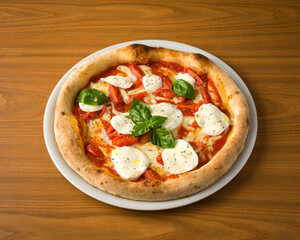 plate with pizza, cherry tomatoes, mozzarella and basil on wooden table