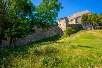 Ancient walls of a fortified city with a green grass meadow.