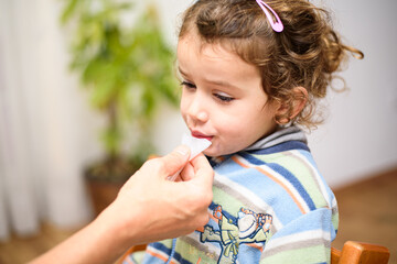 A three-year-old girl spits into a saliva test tube for covid19 antigens.