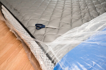Unwrapping new mattress from its plastic wrap with scissors, it expands quickly.