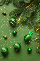 Christmas balls and fir branches on green background