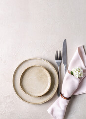 Beige ceramic plates and a pink napkin on a beige stone table. Top view, copy of space. Table setting, menu background, layout, recipe background, food flat layout