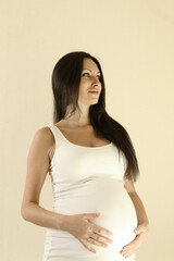 Beautiful young pregnant brunette woman touching  belly.