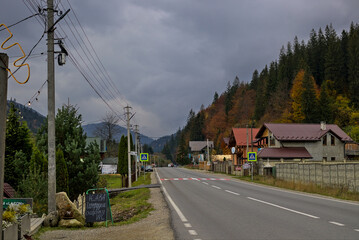 Ivano-Frankivsk Oblast, Ukraine - A road in a small village located in a mountain valley. Cloudy day. The tops of high mountains are hidden by clouds.