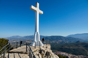 Large white stone cross on the hill of Santa Catalina in Jaén (Spain) and its views over mountains of crops