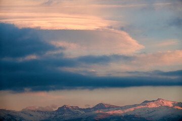Huge white lenticular clouds over Sierra Nevada in Granada at sunset