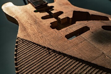 Wooden electric guitar's body unfinished on dark background