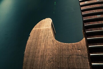 Wooden electric guitar's body unfinished on dark background