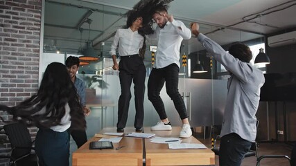 Multiracial colleagues dancing in office celebrating victory company success good deal man and woman moving on table in conference room happy diverse business people having fun corporate party concept