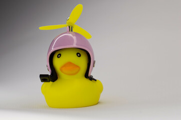 yellow rubber duck on white background in pink helmet with yellow propeller