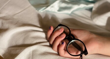 Fototapeta na wymiar A teenage girl is sleeping sweetly from a comfortable bed, glasses remained in her hand.