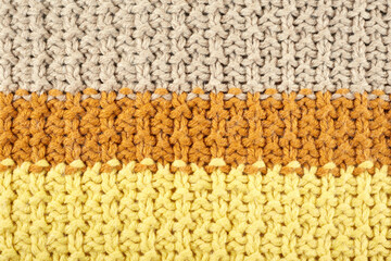 Knitted pattern close-up. Pattern of yellow, terracotta and light brown threads